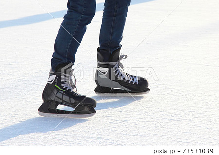 the legs of a man skating on the ice rink 73531039