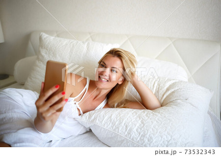 young woman on a white bed is working talking by videoconference 73532343