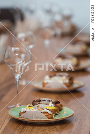 served table for food and vine tasting. Eclairs with different ganache and icing with different toppings served table for food and vine tasting. Eclairs with different ganache and icing with different toppings 73533903