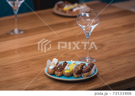 served table for food and vine tasting. Eclairs with different ganache and icing with different toppings served table for food and vine tasting. Eclairs with different ganache and icing with different toppings 73533906