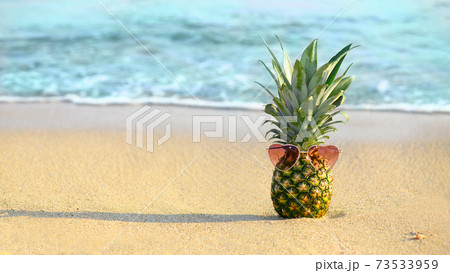 Fashion pineapple with heart shape glasses on a sandy beach 73533959