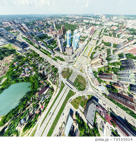 Aerial city view with crossroads and roads, houses, buildings, parks and parking lots. Sunny summer panoramic image 73535014