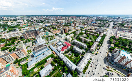 Aerial city view with crossroads and roads, houses, buildings, parks and parking lots. Sunny summer panoramic image 73535020