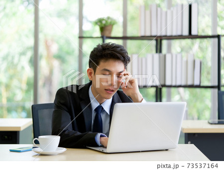 Young asian employee take a nap in the office while working on laptop computer. Young asian employee take a nap in the office while working on laptop computer. 73537164