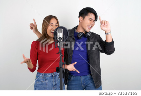 Young asian couples with headphones sing in chorus with microphone and pop filter on tripod stand. 73537165