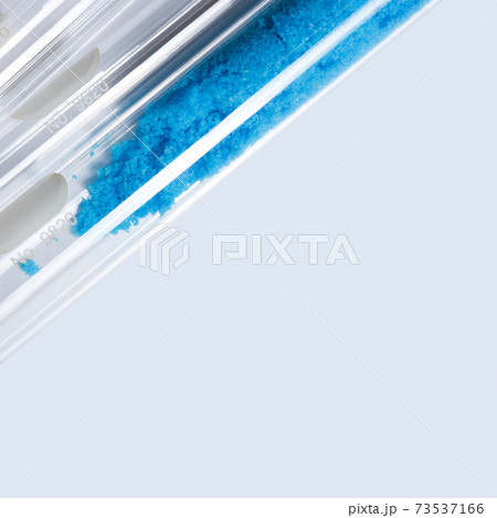 Blue flake chemicals in test tube, Copper(II) sulfate. Cosmetic chemicals ingredient on blue background. Close up Blue flake chemicals in test tube, Copper(II) sulfate. Cosmetic chemicals ingredient on blue background. Close up 73537166