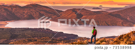 Travel hiking man looking at nature landscape sunset panoramic banner background. Adventure traveler in outdoor New Zealand, backpacking hiker. Copy space panorama 73538998