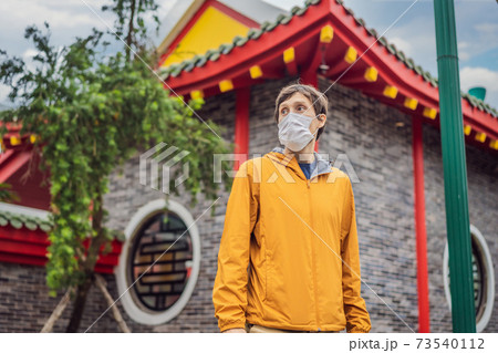 traveler in medical mask stopped on the street and looking at the Japanese, Chinese, Korean, Vietnamese traditional building. Tourists travel in Asia after the coronavirus epidemic 73540112