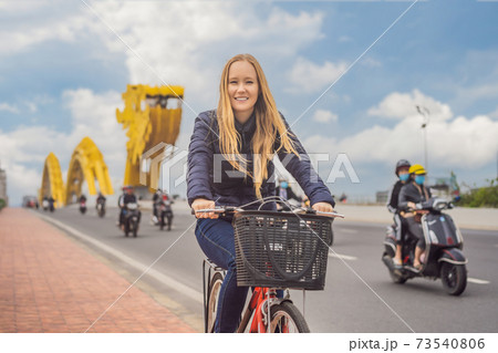 Woman rides a bicycle on the dragon bridge in Da Nang Woman rides a bicycle on the dragon bridge in Da Nang 73540806