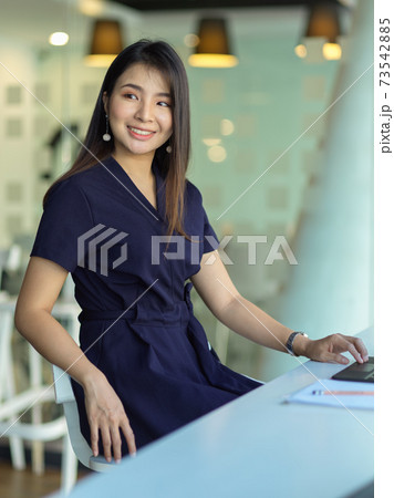 Businesswoman smiling to camera while sitting at worktable in office room 73542885