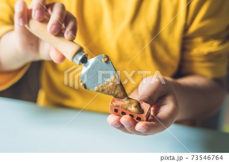 Close up of child's hands playing with real small clay bricks at the table. Toddler having fun and building out of real small clay bricks. Early learning. Developing toys. Construction concept Close up of child's hands playing with real small clay bricks at the table. Toddler having fun and building out of real small clay bricks. Early learning. Developing toys. Construction concept 73546764