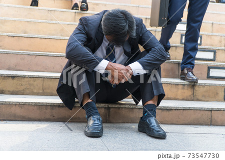 Businessman sitting on the stairs fixing a failing sense. Businessman sitting on the stairs fixing a failing sense. 73547730