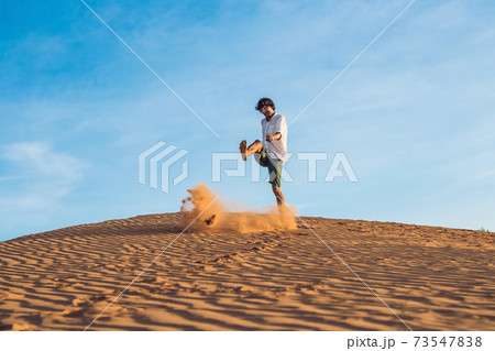 A man is kicking sand in a red desert. Splash of anger concept 73547838
