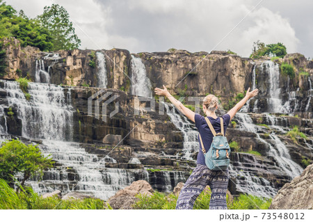 Young woman hiker, tourist on the background of Amazing Pongour Waterfall is famous and most beautiful of fall in Vietnam. Not far from Dalat city estimate 45 Km. Dalat, Vietnam 73548012
