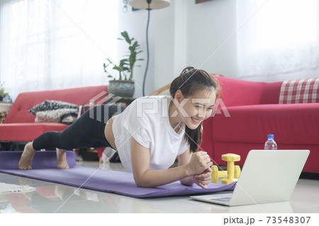 Fit woman doing yoga plank and watching online tutorials. Fit woman doing yoga plank and watching online tutorials. 73548307