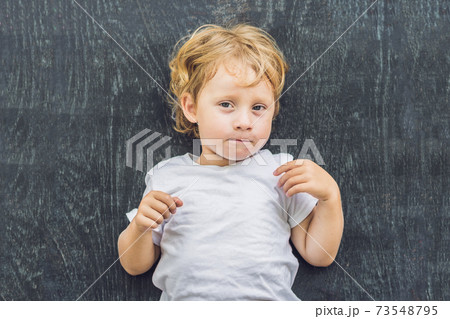 Top view of a little blond kid boy with space for text and symbols on the old wooden background. Concept for confusion, brainstorming and choice Top view of a little blond kid boy with space for text and symbols on the old wooden background. Concept for confusion, brainstorming and choice 73548795