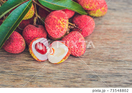 Fresh litchi fruit on an old wooden background Fresh litchi fruit on an old wooden background 73548802