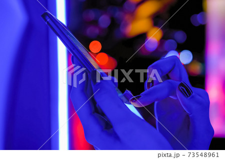 Woman using smartphone at exhibition with blue illumination - close up view Woman using smartphone at exhibition with blue illumination - close up view 73548961