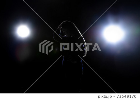 Silhouette of sad woman isolated on dark background in lanterns light Silhouette of sad woman isolated on dark background in lanterns light 73549170