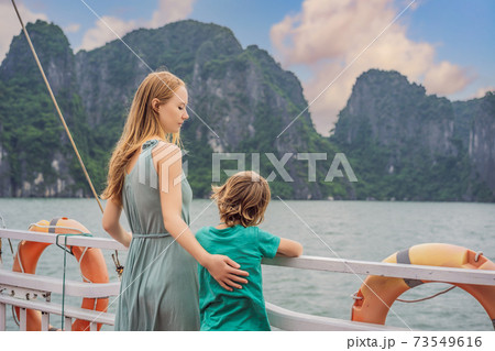 Mom and son travelers is traveling by boat in Halong Bay. Vietnam. Travel to Asia, happiness emotion, summer holiday concept. Traveling with children concept. After COVID 19. Picturesque sea landscape 73549616