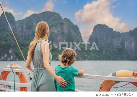 Mom and son travelers is traveling by boat in Halong Bay. Vietnam. Travel to Asia, happiness emotion, summer holiday concept. Traveling with children concept. After COVID 19. Picturesque sea landscape 73549617
