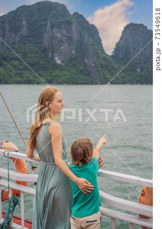 Mom and son travelers is traveling by boat in Halong Bay. Vietnam. Travel to Asia, happiness emotion, summer holiday concept. Traveling with children concept. After COVID 19. Picturesque sea landscape 73549618