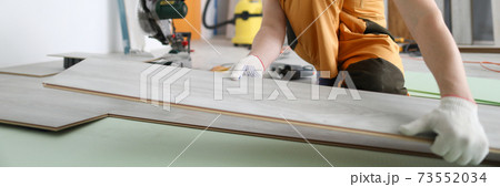 Specialist hold laminate in his handand put it on floor. 73552034