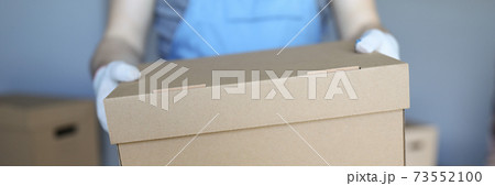 Man in overalls and gloves hold large cardboard box in his hand close-up. Man in overalls and gloves hold large cardboard box in his hand close-up. 73552100