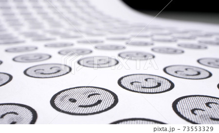 background from smiles. icons with smiling faces on a sheet of paper. close-up 73553329