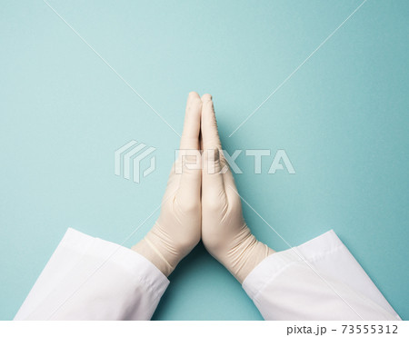 two male hands in white latex gloves, doctor's palms on a blue background in a prayer position two male hands in white latex gloves, doctor's palms on a blue background in a prayer position 73555312