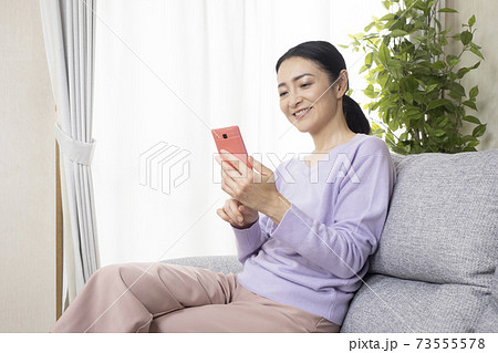 スマホの画面を見て微笑む女性 スマホの画面を見て微笑む女性 73555578