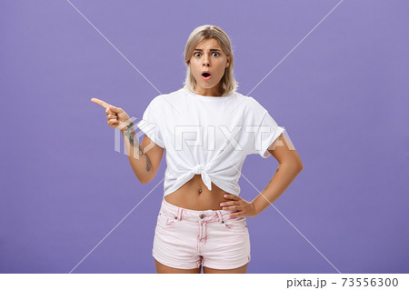 Girl being unhappy with unfair thing happened. Shocked displeased complaining, confused woman with tanned skin blond hair and tattoos opening mouth and frowning from jealousy or regret pointing left Girl being unhappy with unfair thing happened. Shocked displeased complaining, confused woman with tanned skin blond hair and tattoos opening mouth and frowning from jealousy or regret pointing left 73556300