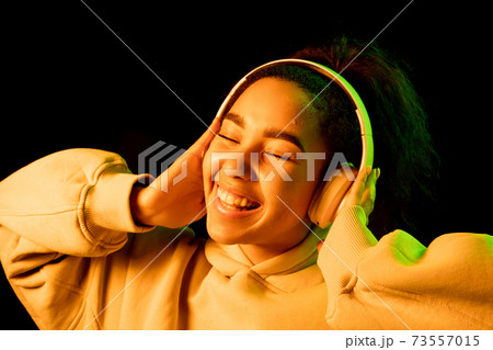 African-american woman's portrait isolated on dark studio background in orange-green neon light 73557015
