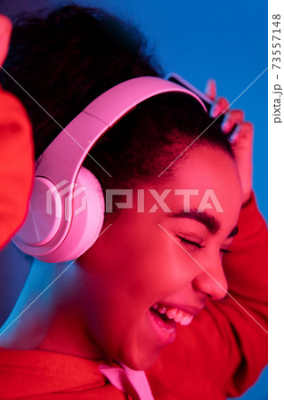 African-american woman's portrait isolated on blue studio background in multicolored neon light 73557148