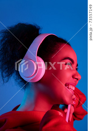 African-american woman's portrait isolated on blue studio background in multicolored neon light 73557149