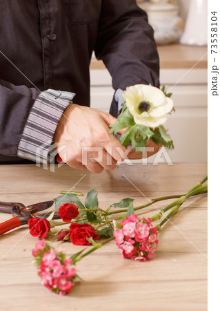 Young male florist cutting a flowers at flower shop, close up 73558104