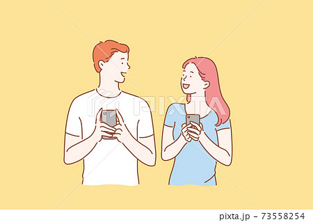 Concept of a young couple in love excited man and woman smiling. Boy and Girl meet or talk, both using mobile phones 73558254