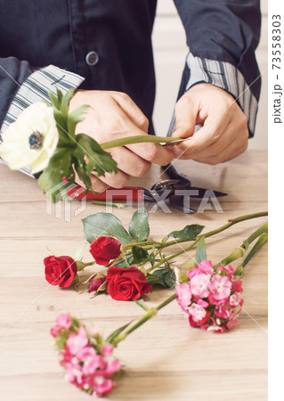 Young male florist cutting a flowers at flower shop, close up 73558303