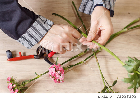 Young male florist cutting a flowers at flower shop, close up 73558305