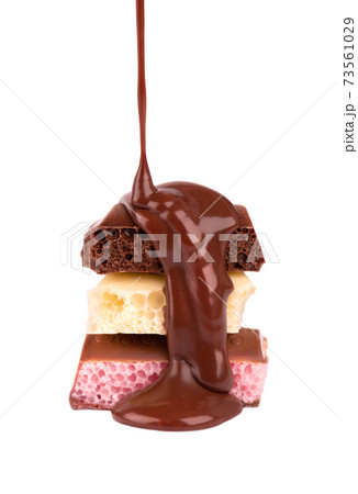 Mix of porous chocolate pieces and chocolate syrup, isolated on white background. Black, white and pink aerated chocolate. 73561029