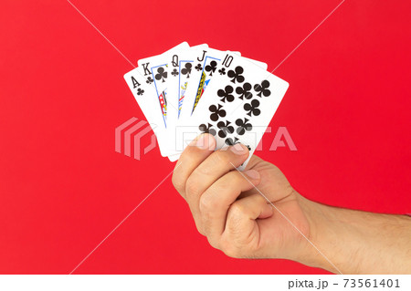 Male hand holding combination of royal flush poker cards on red background. Casino luck fortune concept Male hand holding combination of royal flush poker cards on red background. Casino luck fortune concept 73561401