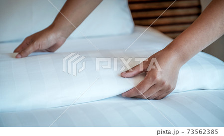 Hands of hotel maid making the bed in the luxury hotel room ready for tourist travel Hands of hotel maid making the bed in the luxury hotel room ready for tourist travel 73562385