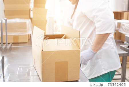 A worker controls the weight and quality of products in a box in a food production, background, Sanitary control at the workplace A worker controls the weight and quality of products in a box in a food production, background, Sanitary control at the workplace 73562406
