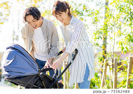 赤ちゃんを抱っこしながら外を歩く夫婦 73562489