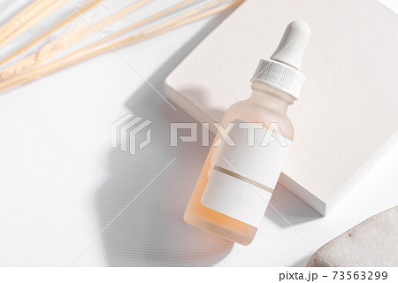 Close-up yellow serum essence in glass bottle on white stand background. Isolated skincare oil 73563299