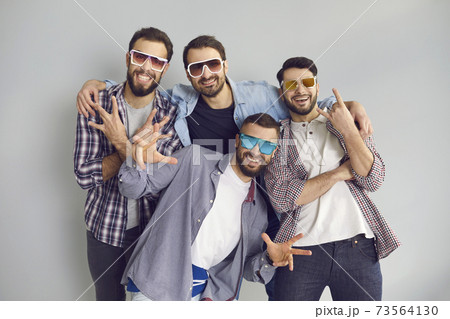 Group of young friends in sunglasses looking at camera and posing for funny photo Group of young friends in sunglasses looking at camera and posing for funny photo 73564130