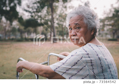 Asian senior or elderly old lady woman patient walk with walker in park with copy space, healthy strong medical concept 73564542