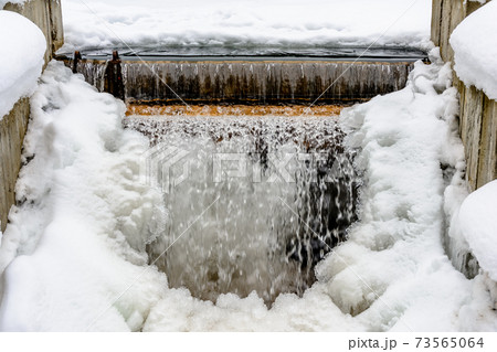 A small frozen waterfall, cold water, snow and ice, winter and frost. 73565064