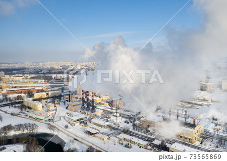 In the winter city, the factory's chimneys are smoking. The concept of air pollution. Environmental pollution by industrial waste In the winter city, the factory's chimneys are smoking. The concept of air pollution. Environmental pollution by industrial waste 73565869