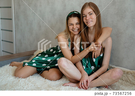Lifestyle, friendship concept - two beautiful girls dressed in pajamas hugging Lifestyle, friendship concept - two beautiful girls dressed in pajamas hugging 73567256